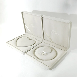 Macro view of cream-colored jewelry gift boxes featuring heart and round inner inserts