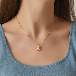 3D geometric bear pendant necklace in gold finish on model with blue sweater