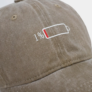 Detail of a low battery 1% print on a washed khaki vintage cotton baseball cap