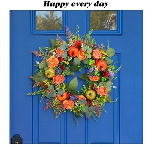 Detailed close-up of autumn wreath with orange pumpkins and artificial purple flowers