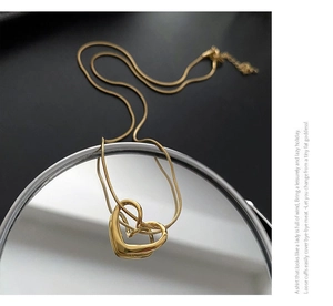 Detail of gold hollow heart pendant on snake chain over mirror reflection background