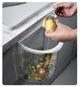 Wall-mounted transparent kitchen trash can hanging on cabinet door for food waste