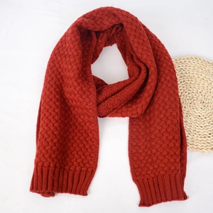 Detailed macro view of red knit scarf featuring textured weave patterns and ribbed edges