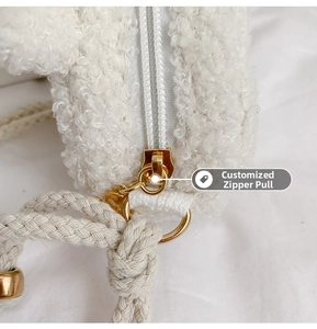 Detail of white faux shearling bag with customized gold zipper pull and woven handle