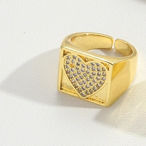 Macro view of gold adjustable wide ring featuring a square face and pavé heart design