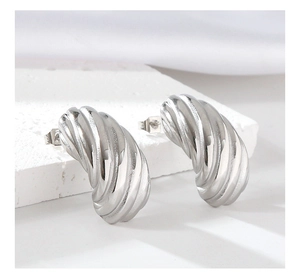 Macro shot of silver curved twist earrings with polished finish on a stone surface