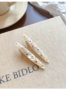 Détail de barrettes en acrylique marbré ornées de strass multicolores brillants