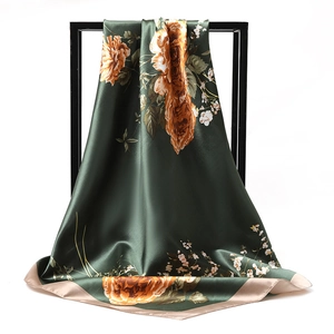 Detail of dark green square satin scarf with gold floral patterns on a display stand