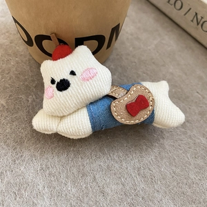 Detailed close-up of a plush knit puppy hair clip with cherry and denim overalls