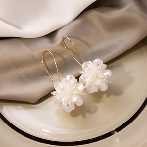 Exaggerated white floral drop earrings with faceted petals on long gold hooks