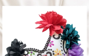 Detail of Day of the Dead mask featuring colorful artificial flowers and glitter patterns