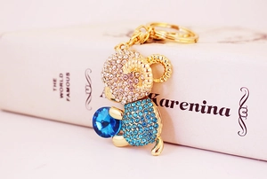 Detail of a gold sheep keychain with blue crystals resting on a classic book