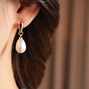 Close-up of elegant French vintage teardrop pearl earrings worn on a model's ear