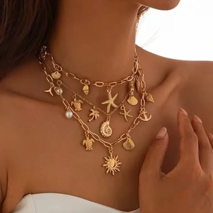 Layered gold necklace with sea star shell turtle and anchor charms on model