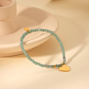 Detail of green natural stone beaded bracelet with a polished gold heart pendant