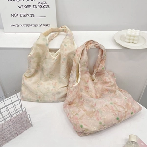 Detail view of lightweight fabric tote bags featuring delicate bow embroidery and floral prints