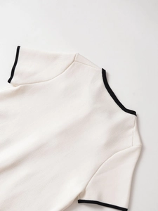 Detail of the white knitted short sleeve top with black contrast trim on the neckline