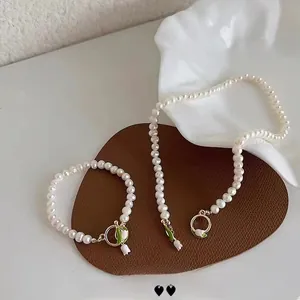 Detailed view of pearl necklace and bracelet set with tulip toggle clasp and floral charms