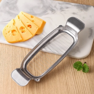 Stainless steel cheese slicer with cutting wire and fresh yellow cheese on wooden table