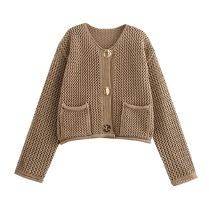 Detailed view of textured knit cardigan with three gold buttons and front pockets