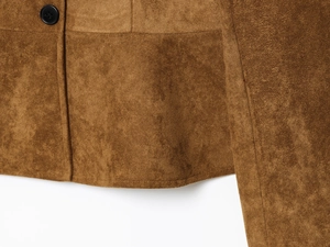 Detail view of brown suede jacket hem showing fine stitching and polished black button