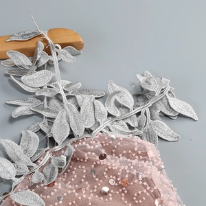 Detail of pink mesh fabric with silver leaf embroidery, sequins and beadwork on a dress