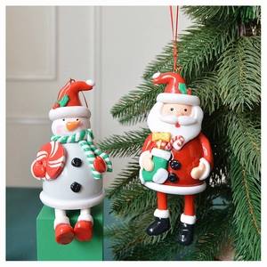 Close-up of ceramic snowman and Santa hanging ornaments on a green Christmas tree