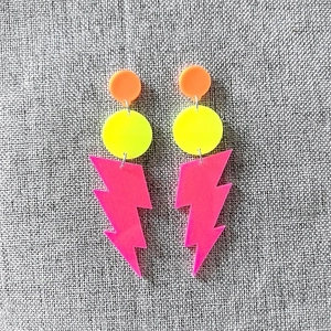 Detail of neon acrylic lightning bolt earrings featuring layered fluorescent geometric shapes