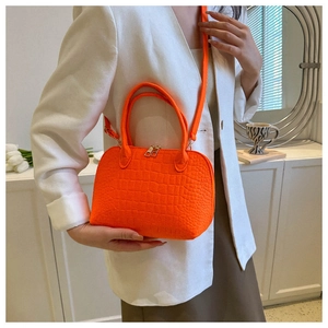 Macro detail of bright orange faux crocodile leather shell bag with gold zipper and handle