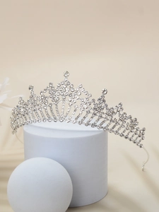 Close-up of a silver vintage bridal tiara with sparkling rhinestones on a white stand