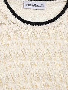Détail du haut en maille crochetée avec bordure contrastée noire et étiquette de marque