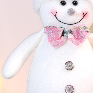 Nahaufnahme eines weichen weißen Schneemanns mit rosa karierter Schleife und Knöpfen