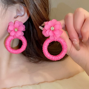 Detail of pink floral woven earrings with rhinestone center and raffia hoop texture