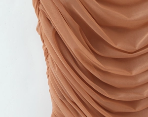 Gros plan sur le tissu en maille caramel montrant les détails de plissage et de fronces