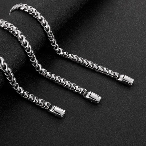 Trois rangées de colliers élégants en acier inoxydable argenté sur fond noir texturé