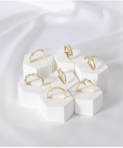Close-up of assorted gold rings with pearls and diamonds on white hexagonal displays