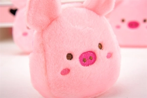 Close-up of pink plush pig coin purse featuring delicate facial embroidery and soft texture