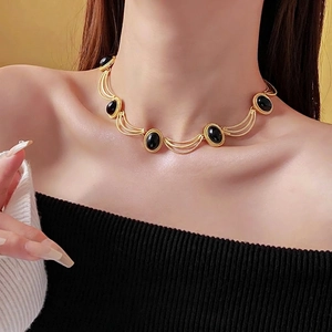 Vintage gold metal necklace with black oval stones shown on an elegant model