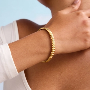 Élégant bracelet en perles d'acier inoxydable plaqué or 18 carats au poignet d'une femme
