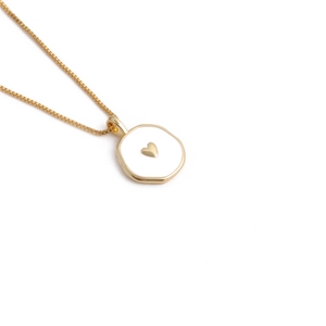 Macro view of gold heart pendant necklace with white enamel inlay and box chain