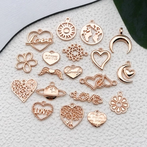 Detailed flat lay of rose gold alloy charms including hearts, moons, and solar patterns