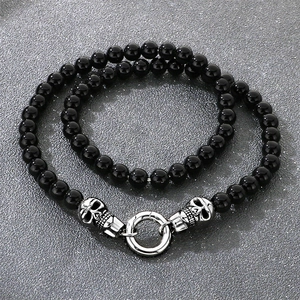 Détail d'un collier de perles hip hop avec breloques crâne argentées et touches de diamant