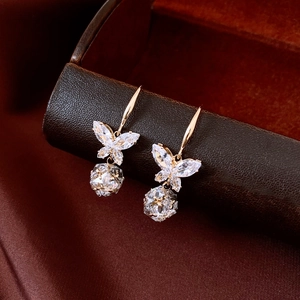 Détail des boucles d'oreilles papillon en zircon avec pendentif sur support en cuir brun