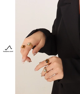 Detail of tiger eye and dalmatian stone rings with gold stainless steel chain bands