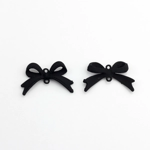 Macro detail of matte black alloy bow connectors with fine stitched texture for DIY crafts