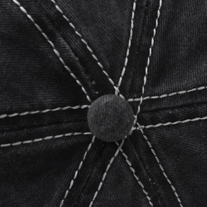 Macro shot of contrast white stitching on black washed cotton baseball cap crown