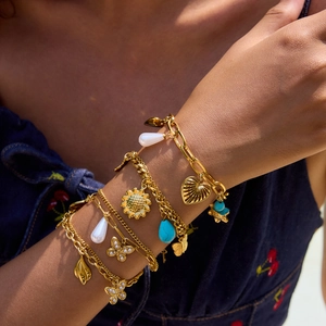 Bracelet multicouche en acier doré avec breloques papillon et perles au poignet d'un mannequin