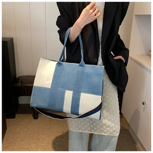 Large denim tote bag with color blocking design shown on a model in a home setting