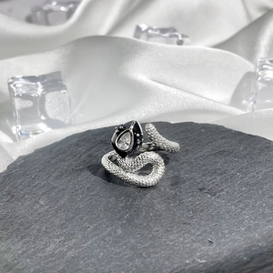 Macro shot of silver snake ring with scale textures and black head featuring clear crystal