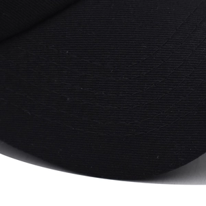 Macro detail of black cotton baseball cap brim showing precise four-line stitching texture